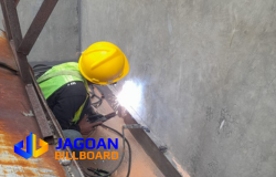 Proses pengelasan rangka oleh teknisi Jagoan Billboard di area konstruksi beton.