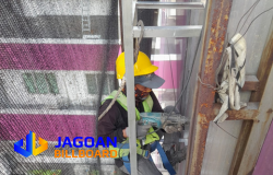 Teknisi Jagoan Billboard sedang melakukan pemasangan atau perawatan struktur di ketinggian dengan peralatan keselamatan lengkap.